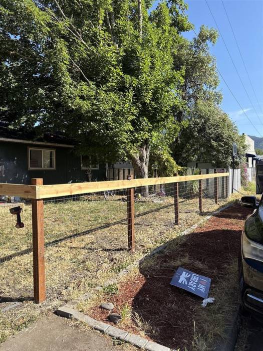 Custom fence with cedar posts, a wood top rail and welded wire infill installed along a front yard in Grants Pass, Oregon.